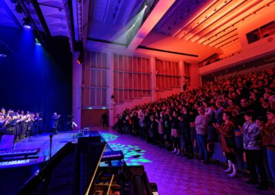 Seisten taputtava konserttiyleisö ja yleisöä taputtaen kiittävä kuoro.