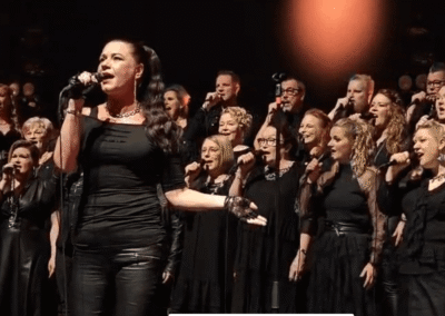 Mustiin pukeutunut solisti ja mustiin pukeutunut kuoro esiintymässä konsertissa.