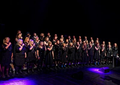 Mustiin pukeutunut kuoro lavalla sinivioleteissa valoissa.