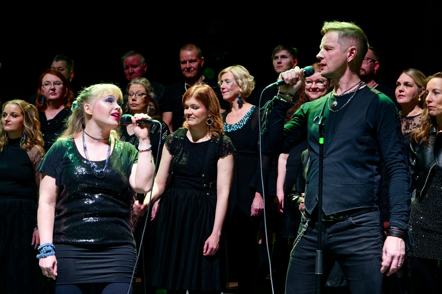 Mustiin pukeutunut kuoro esiintyy lavalla. 