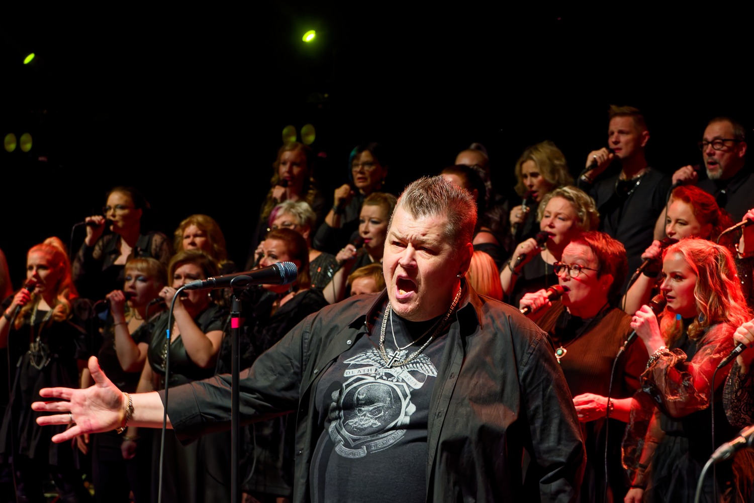 Mustiin pukeutunut kuoro esiintyy lavalla. 