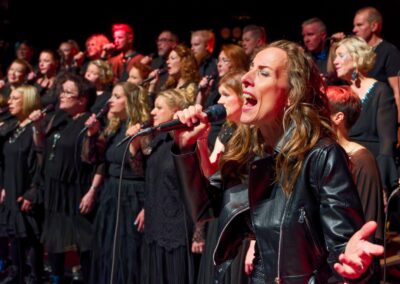 Solisti ja kuoro laulavat mikrofoneihin.