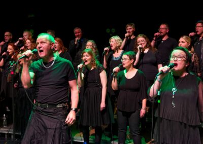 Duettopari ja kuoro esiintyvät vihreissä valoissa.