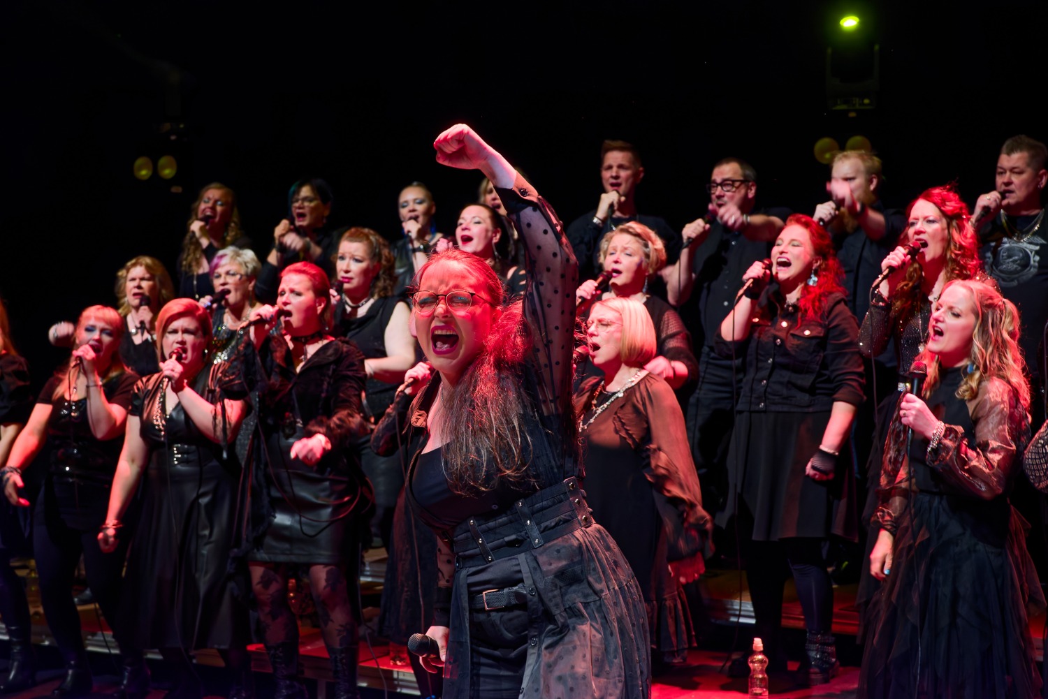 Mustiin pukeutunut kuoro esiintyy lavalla. 