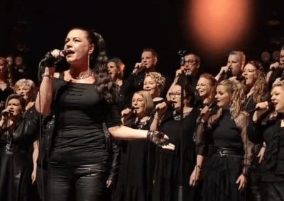 Solisti Mirva Janhunen ja kuoro esiintymässä lavalla.